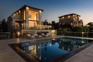 uma casa com piscina em frente a uma casa em Magnifique villa avec piscine au bord de mer em Chorafakia