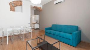 uma sala de estar com um sofá azul e uma mesa em Italianway - The B Village New em Milão