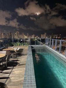 a swimming pool on the roof of a building at night at One way in João Pessoa