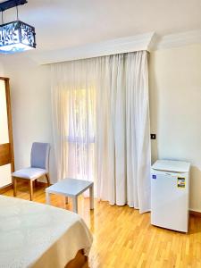 a bedroom with a bed and a chair and a window at Golden Rose- men only in 6th Of October