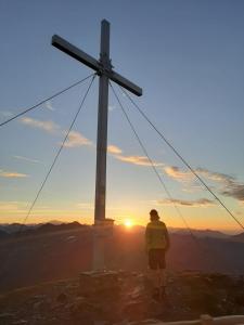 a man standing next to a cross on top of a mountain at Frühstückspension Lemberger in Dellach im Drautal