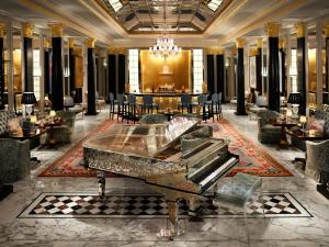 Un piano de cola en un vestíbulo con una mesa y sillas. en The Dorchester - Dorchester Collection, en Londres