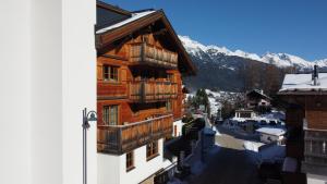 a wooden building with balconies on a street with mountains at ARLhome Lodge - Zuhause am Arlberg in Sankt Anton am Arlberg