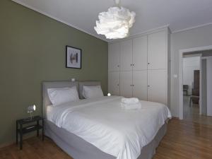 sypialnia z dużym białym łóżkiem z żyrandolem w obiekcie 2 bedroom apartment close to children's hospital w Atenach