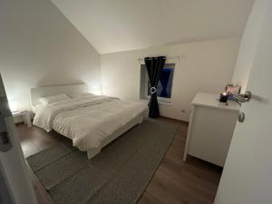 een witte slaapkamer met een bed en een raam bij Chez Charly et Milo - La maison du bonheur in Somme-Leuze