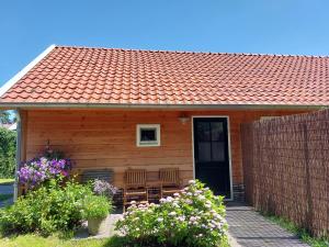 een klein houten huis met een rood dak bij Lodges near the Rhine - Sustainable Residence in Hazerswoude-Rijndijk