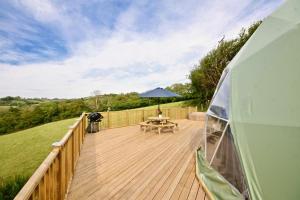 een houten terras met een tafel en een parasol bij Sunridge Geodome with private Hot tub in Plymouth