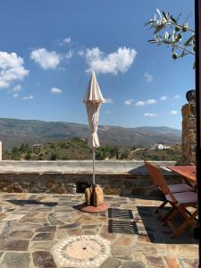een parasol op een patio met uitzicht op de bergen bij Lithos Homes in Volissos