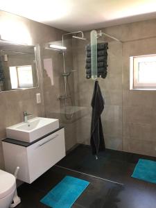 a bathroom with a sink and a shower with blue mats at Ferienwohnung Maldener 