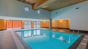 a large swimming pool with blue water in a house at Madame Vacances Les Epinettes in Vaujany