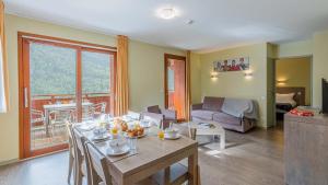 een woonkamer met een tafel en stoelen en een bank bij Madame Vacances Les Epinettes in Vaujany