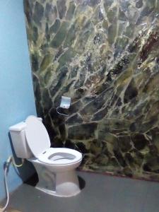 a bathroom with a toilet in front of a stone wall at Baan Saitharn Koh Lanta in Ban Not (1)