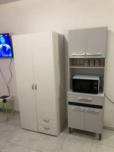 cocina con armario blanco y microondas en Appartement T1, en Saint-Laurent-du-Maroni