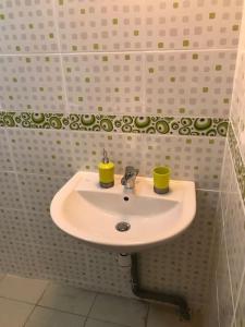 lavabo blanco en un baño con 2 tazas amarillas en Appartement T1, en Saint-Laurent-du-Maroni