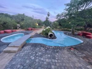a swimming pool in a backyard with a brick patio at Klein Paradys Lodge - Polokwane in Polokwane