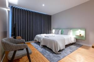 a bedroom with a bed and a chair and a window at Oporto Trendy Formosa in Porto
