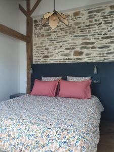 1 cama con 2 almohadas rosas y ventilador de techo en Gîte des Lavandières en Amanlis