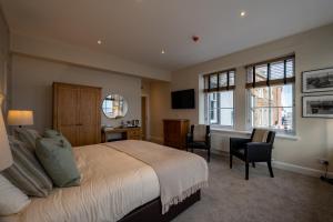 a bedroom with a bed and a desk and chairs at The Waterfront in Anstruther