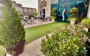 a patio with tables and chairs and grass and plants at Beauty Inn in Ramallah