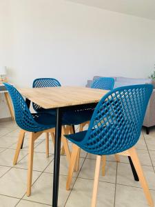 a wooden table with four blue chairs around it at Appartement moderne près de Toulouse in Fonsorbes