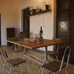 una mesa de madera con sillas y una botella de vino en Uruguay Casa de Época Campestre, en Mercedes