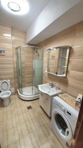 a bathroom with a toilet a sink and a washing machine at Belle Sea View Apartment Mamaia in Mamaia