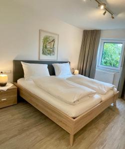 1 dormitorio con 1 cama grande con sábanas blancas y ventana en Landhaus Laugele Ferienwohnungen, en Nußdorf