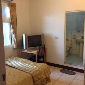 a bedroom with a bed and a tv and a bathroom at Fudu Hotel in Dawu