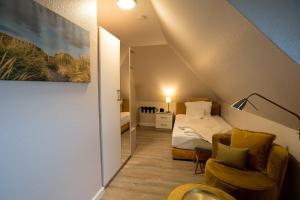 ein Schlafzimmer mit einem Bett und einem Stuhl in einem Zimmer in der Unterkunft Pension Luuward 3 Sterne Hotel in Wenningstedt-Braderup