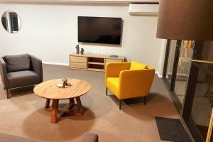 un salon avec une table et une chaise jaune dans l'établissement Bannister Apartment in vibrant central Fremantle, à Fremantle