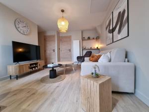 sala de estar con sofá blanco y TV en Appart de standing - Centre-ville, en Chalon-sur-Saône