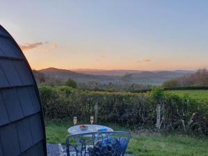 a table with two glasses of wine on top of a field at Odli Glamping - Luxury Glamping Pod in Welshpool +6 photos