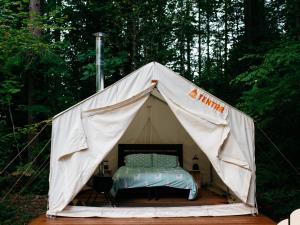 a tent with a bed in it in the woods at Tentrr Signature Site - Cascade Rose Alpaca Farm Stay in Carnation