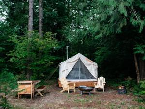 a tent and two chairs and a table and a bench at Tentrr Signature Site - Cascade Rose Alpaca Farm Stay in Carnation
