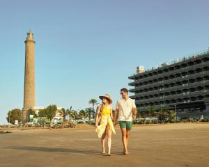 a man and a woman walking on the beach at Hotel Faro, a Lopesan Collection Hotel - Adults Only in Maspalomas