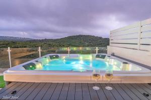 a hot tub on a deck with two wine glasses at סוויטות Sol - סוויטות מהממות בגליל עם בריכה וג'קוזי במתחם in Gornot HaGalil