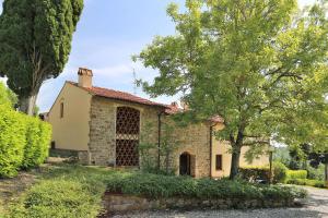 uma antiga casa de pedra com uma árvore e arbustos em Residenza le Colline del Paradiso em Bivigliano