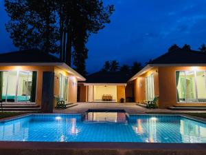una piscina frente a una casa por la noche en Khanom Garden Suite, en Khanom