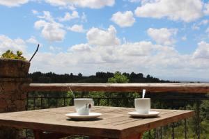 2 tazas de café sentadas en una mesa de madera en un balcón en Casa Rural - Apartamentos Atuvera, en Villanueva de la Vera
