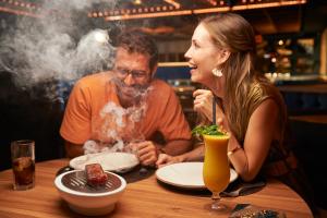 a man and a woman sitting at a table with smoke at Hotel Faro, a Lopesan Collection Hotel - Adults Only in Maspalomas