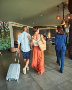 a group of people walking with a suitcase at Hotel Faro, a Lopesan Collection Hotel - Adults Only in Maspalomas