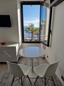 una mesa y sillas blancas en una habitación con una ventana grande en Sanaritz en Sanary-sur-Mer