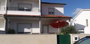 a white house with a red umbrella in front of it at Casa da Cândida in Nazaré