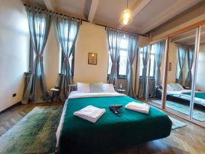 Un dormitorio con una cama verde con toallas y espejos en Sweet Dreams Suites Piata Romana en Bucarest
