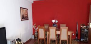 a dining room with a red wall and a table and chairs at Casa da Cândida in Nazaré