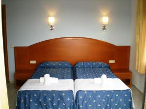 a bed with blue sheets and white pillows at Hotel Bonsol in Lloret de Mar