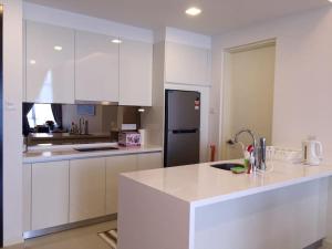 uma cozinha com armários brancos e um frigorífico preto em Tropicana Avenue B32-09, Petaling Jaya em Petaling Jaya