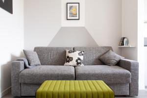 a living room with a couch and a green ottoman at BnButler - Flavio Gioia, 5 - Appartamento con Vista, Citylife in Milan