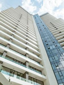 wysoki biały budynek apartamentowy ze szklanymi oknami w obiekcie Secured Lux 1 + 1 apartment - Gym, Sauna & Parking ( EMP 142 ) w mieście Esenyurt