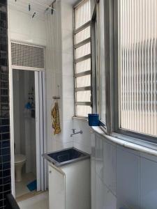 baño con lavabo, ventana y aseo en Luxo apartamento In Copacabana, en Río de Janeiro